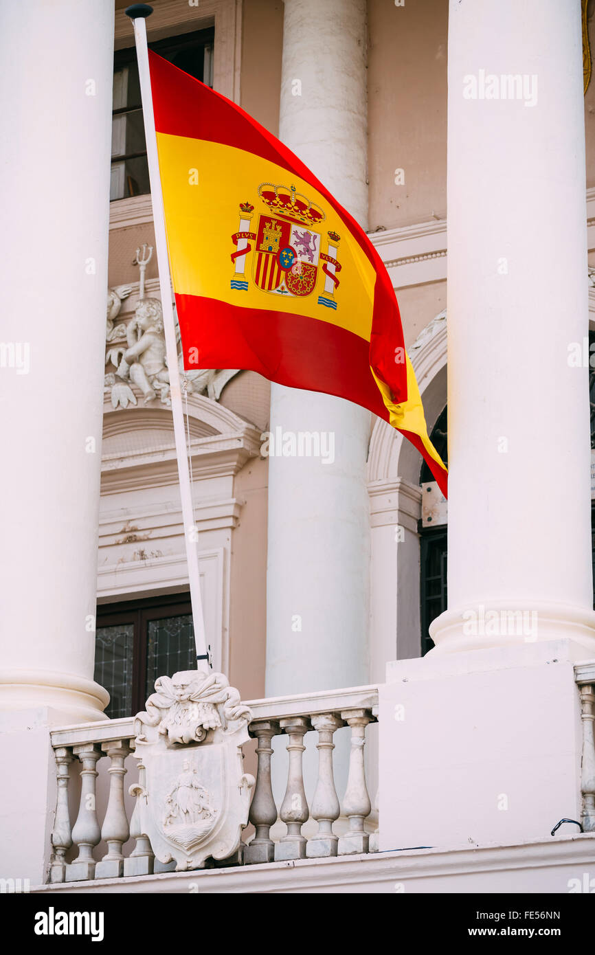 The state flag of the Kingdom of Spain, waving on the facade of the old building. Yellow-red. Stock Photo