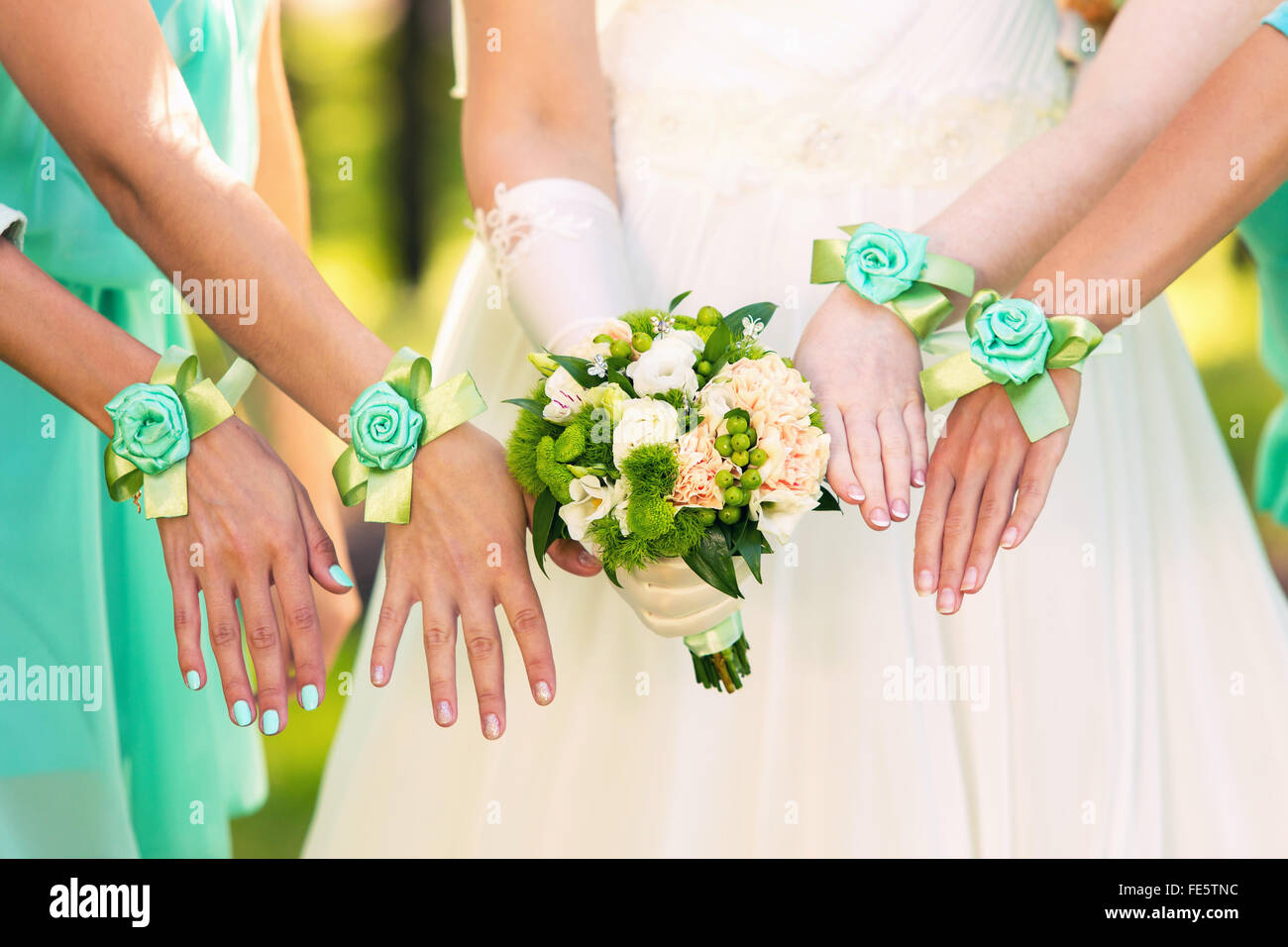 bride with a bouquet and bridesmaids in green dresses and bracelets on  hands Stock Photo - Alamy