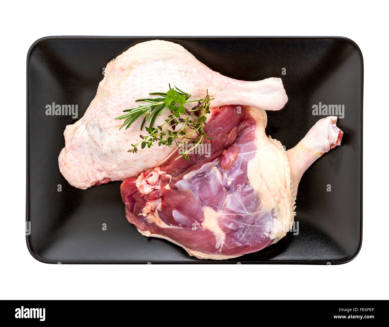 Two Muscovy duck leg with herb on black plate, top view Stock Photo