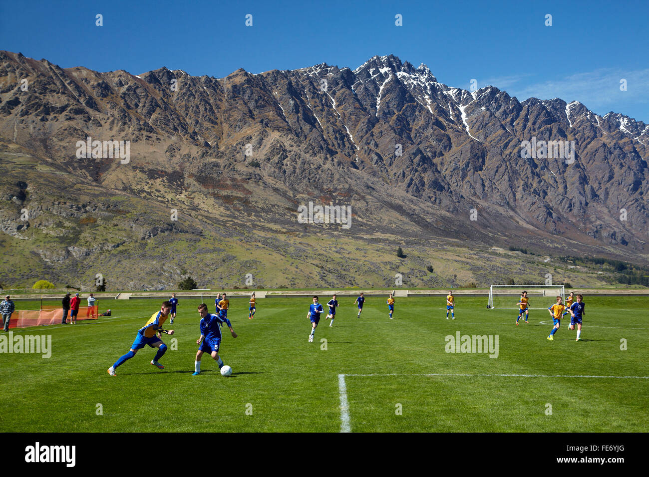 Otago play Nelson at the 13th Grade South Island Football Tournament, beside The Remarkables mountains, Queenstown, Otago, NZ Stock Photo