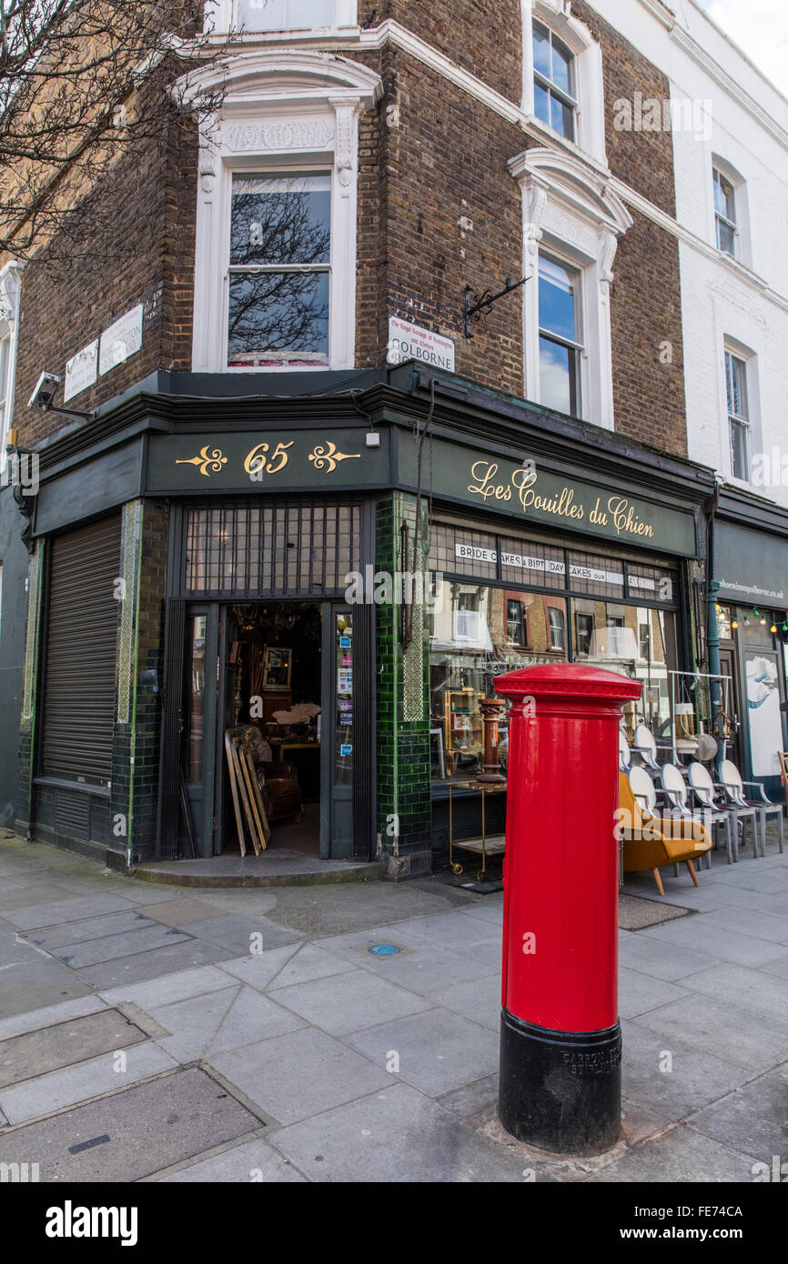 Antique shop with an interesting French name in Portobello Road in London W10 with a red post box in the foreground. Stock Photo