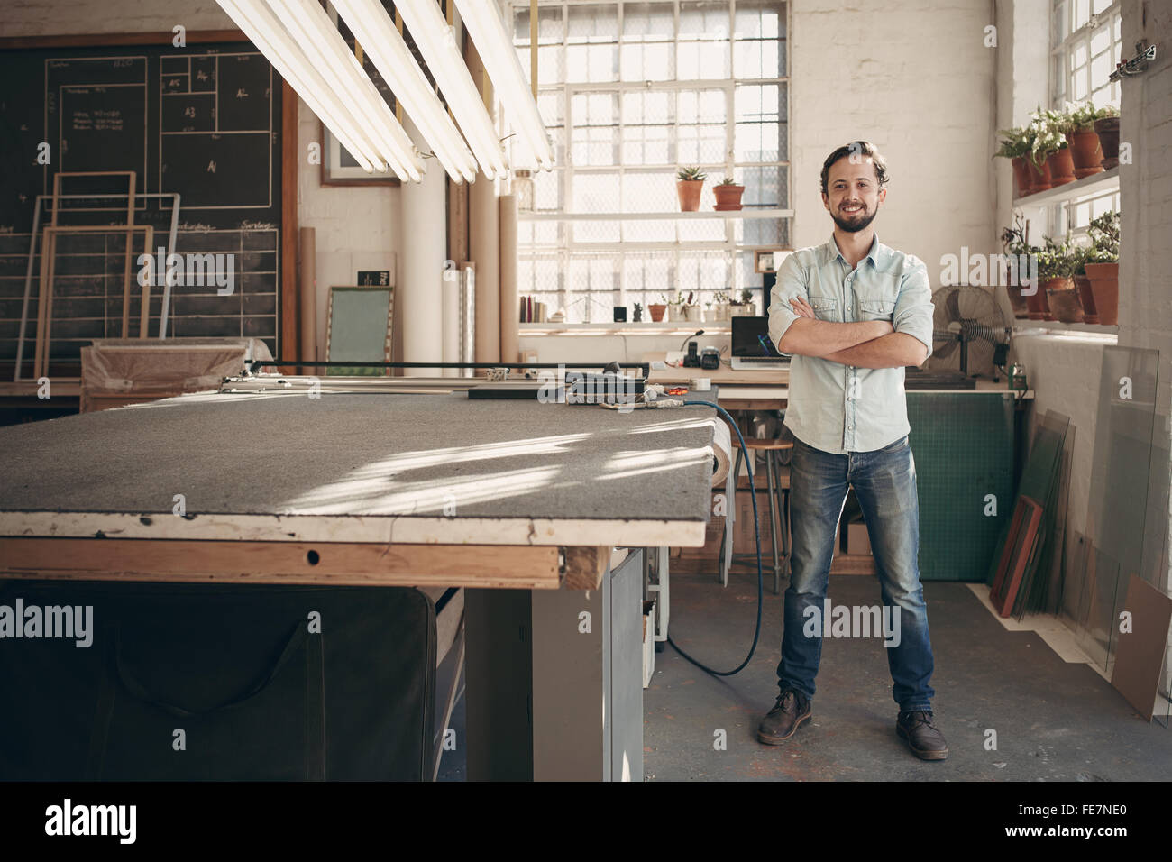 Full length portrait of a young male designer confidently standing with his arms crossed in his workshop and smiling at the came Stock Photo
