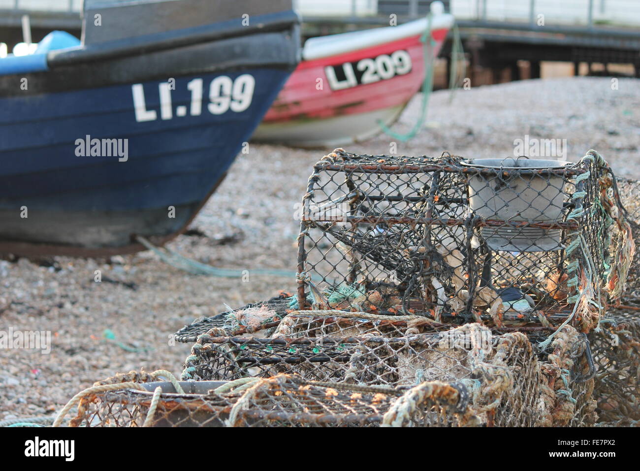 Fishing boat on pebble beach shore with lobster pot traps Stock Photo