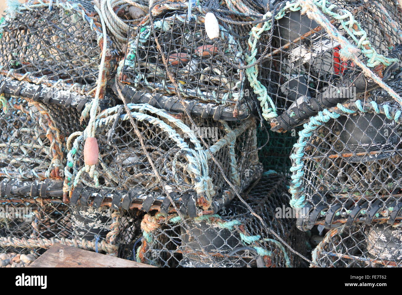 Fishing boat on pebble beach shore with lobster pot traps Stock Photo