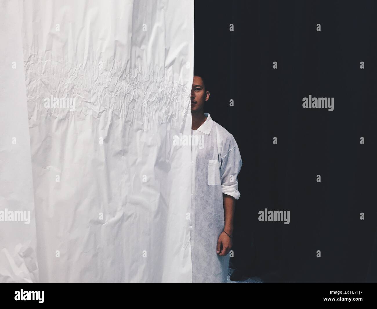 Portrait Of Young Man Standing Behind Curtain Stock Photo