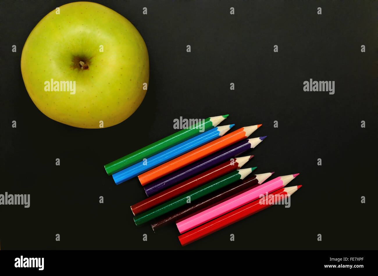 Apple fruit with colorful pencil on black background Stock Photo