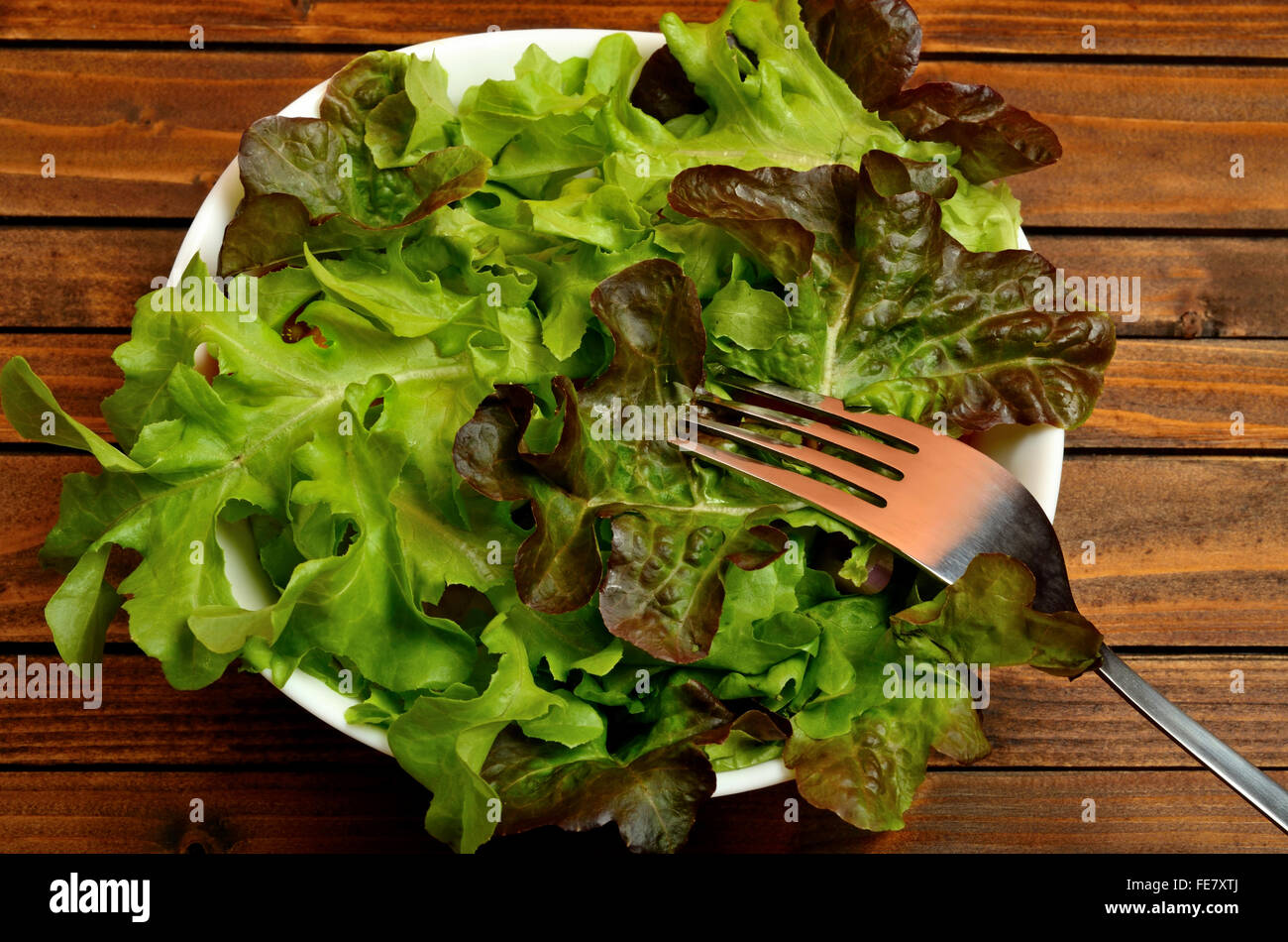 Bowl with lettuce salad on wooden table Stock Photo