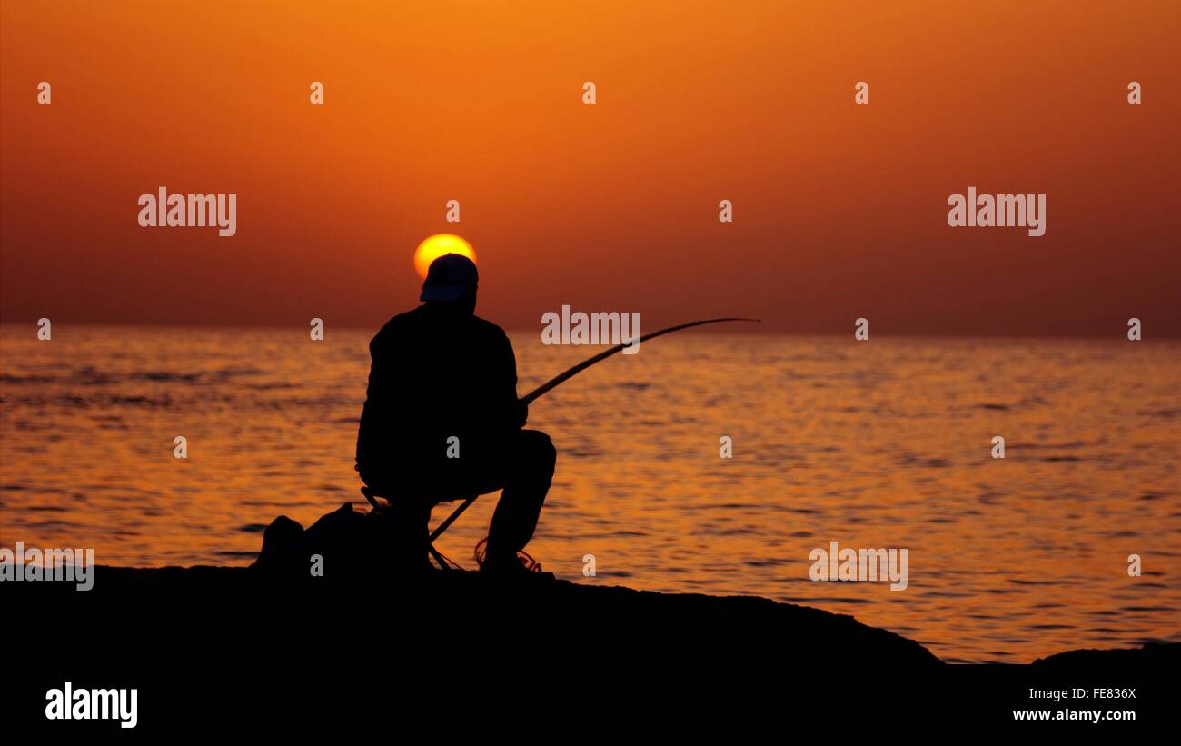 Silhouette Man Fishing In Calm Sea At Sunset Stock Photo - Alamy