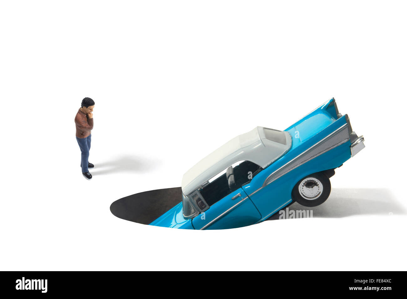 Studio Shot of a Toy Automobile in a Hole with Human Figure Stock Photo