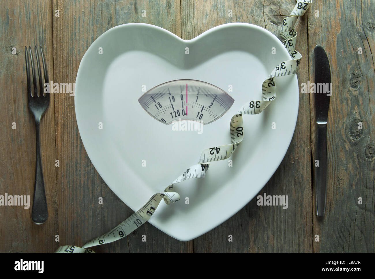 Heart shape plate with weighing scales and tape measure Stock Photo