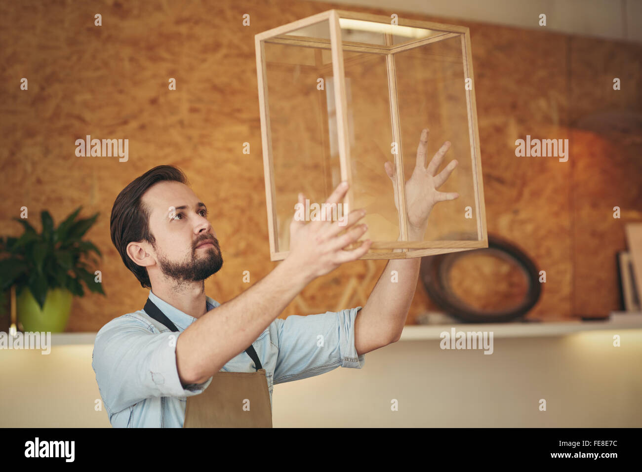 Craftsman holding up a glass and wood display case that he designed and manufactured with skill Stock Photo