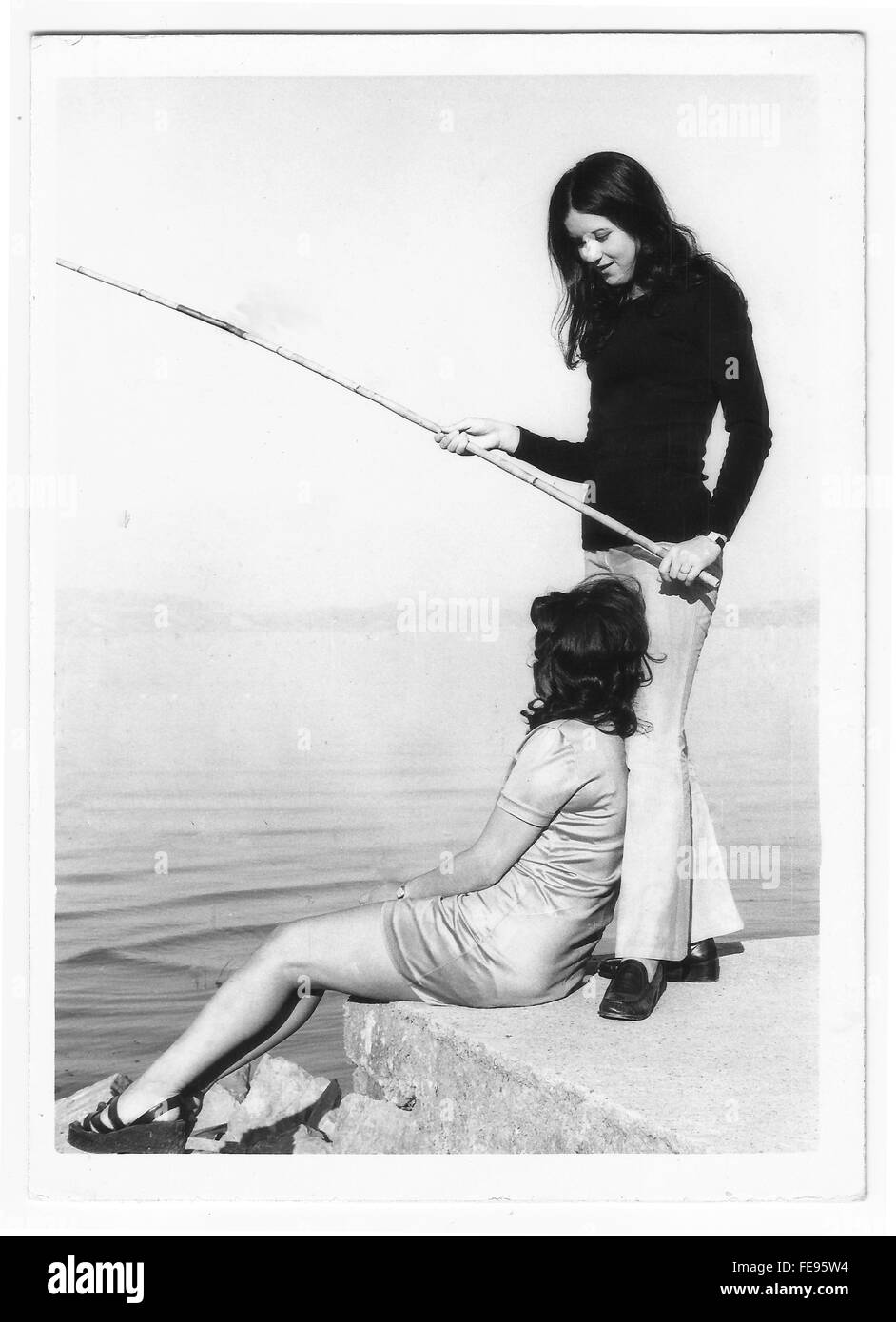 Two friends fishing in the lake. 1960s 1970s black and white film picture Stock Photo