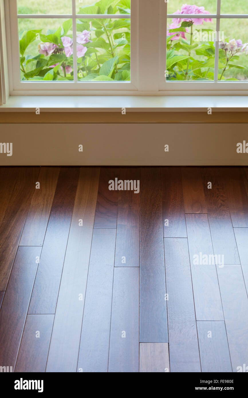 Window light reflecting on clean, shiny, wood hardwood floor. Upscale luxury home interiors details. Stock Photo
