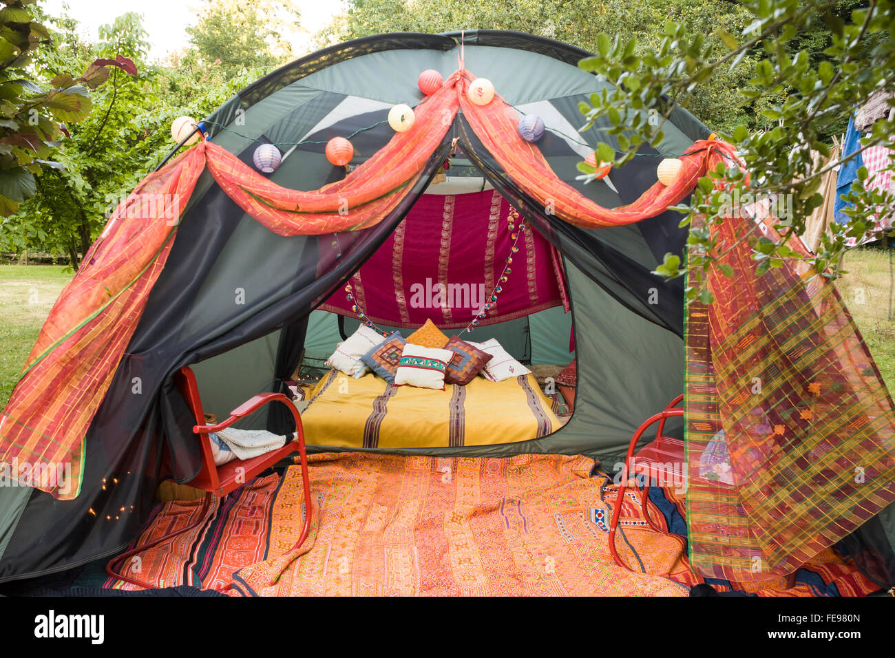 Glamping tent decorated with colorful pillows and blankets. Luxury camping unique summer vacations adventure travel experiences. Stock Photo