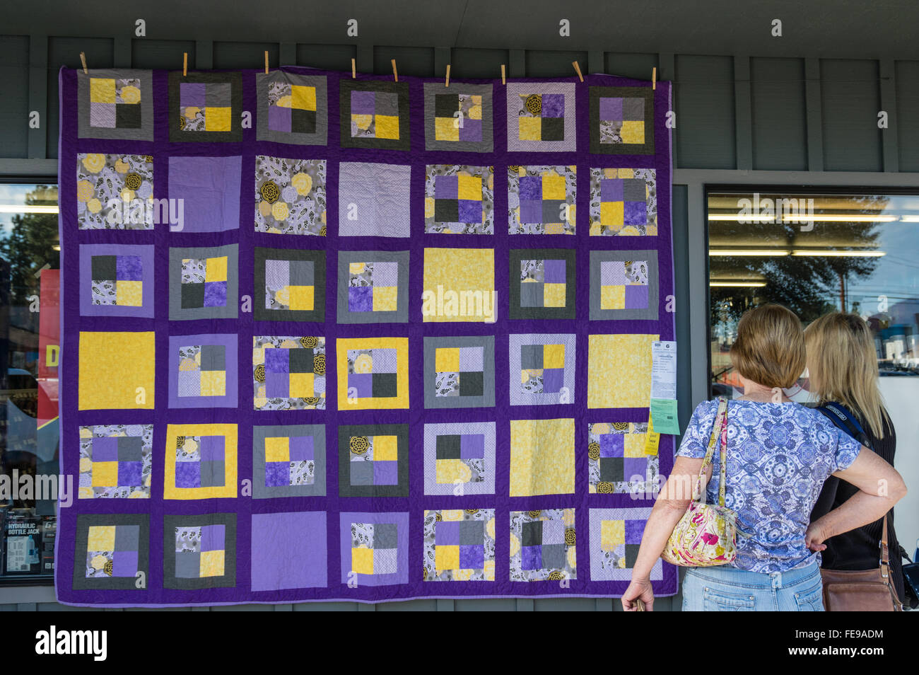 Visitors examine a quilt hanging at the Sisters Outdoor Quilt Show
