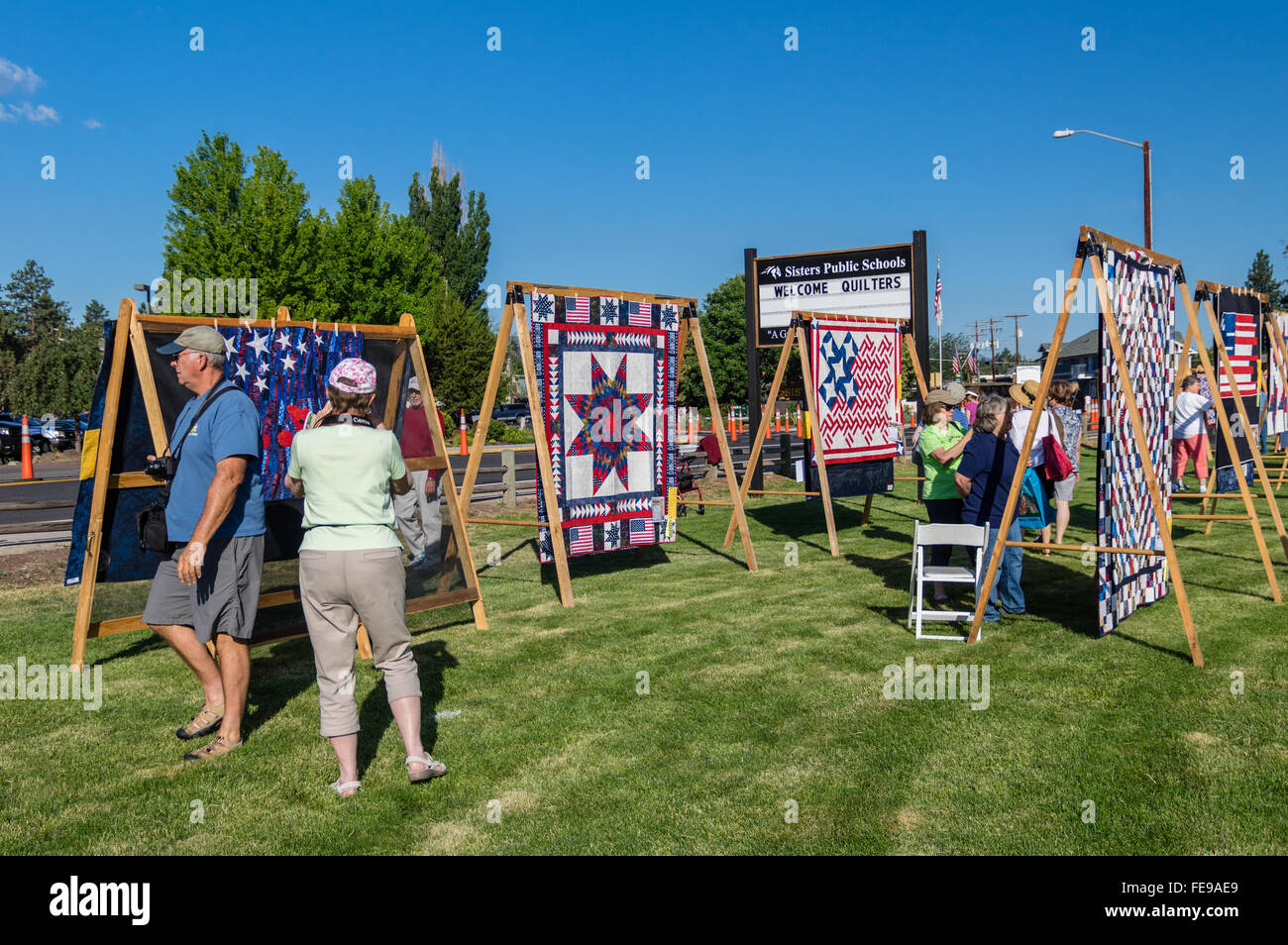 Tourists look at quilts displayed on A frame racks at the Sisters