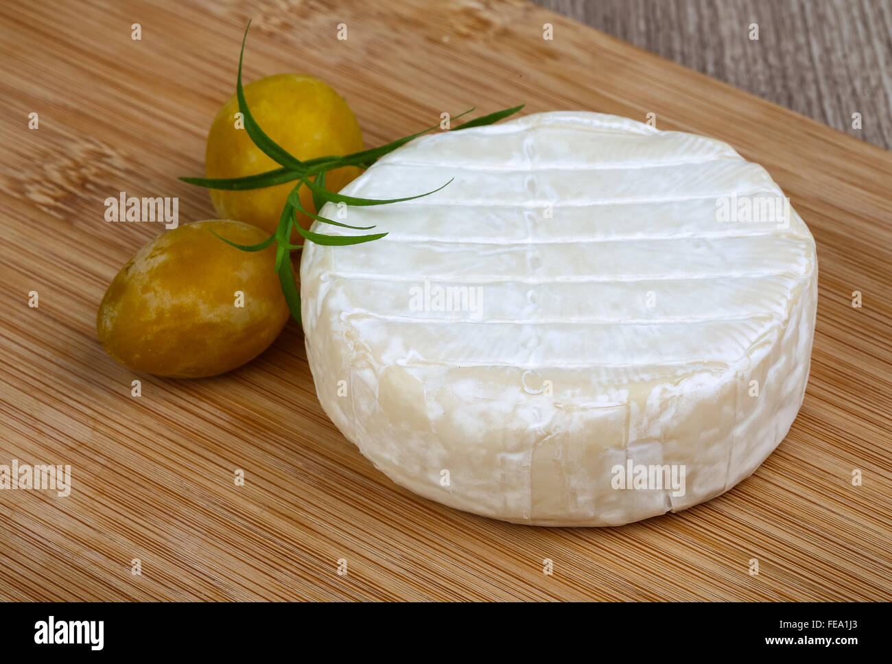 Round Brie cheese with yellow plums and estragon Stock Photo Alamy