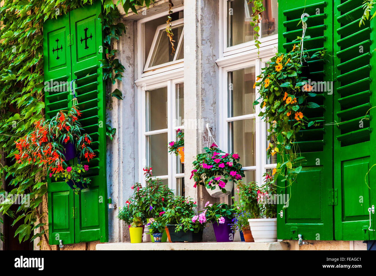 Pretty windows with flower pots and wooden shutters in the old town