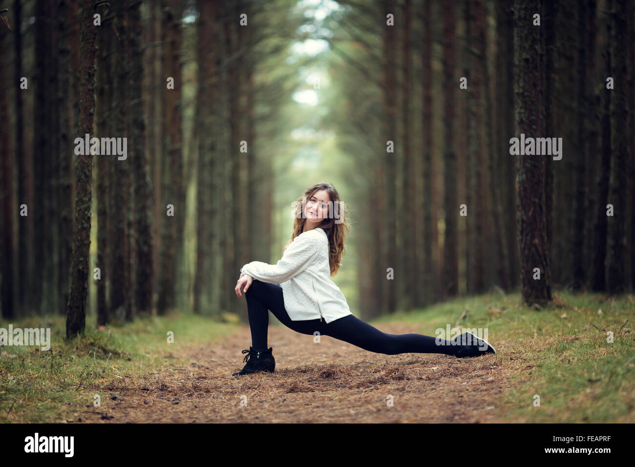 Young professional gymnast makes splits in the forest Stock Photo