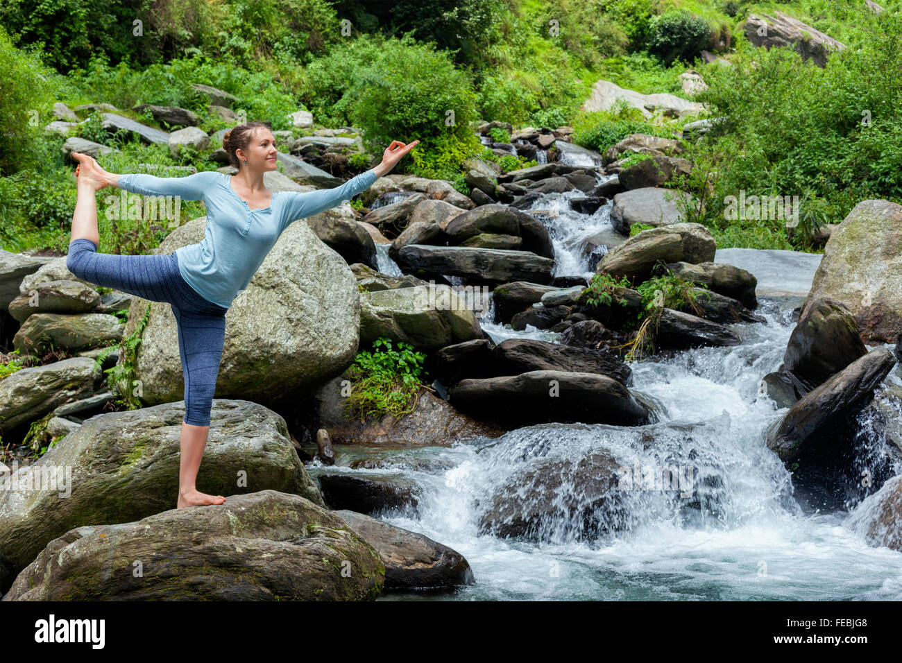 Woman doing yoga asana outdoors at waterfall Stock Photo