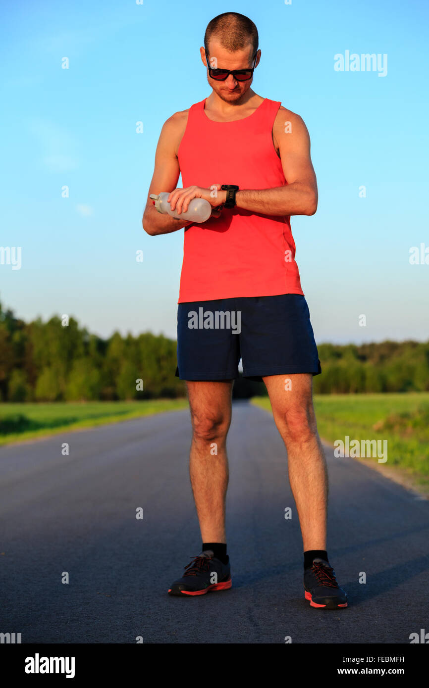 Runner training and checking stopwatch smart watch, cross country