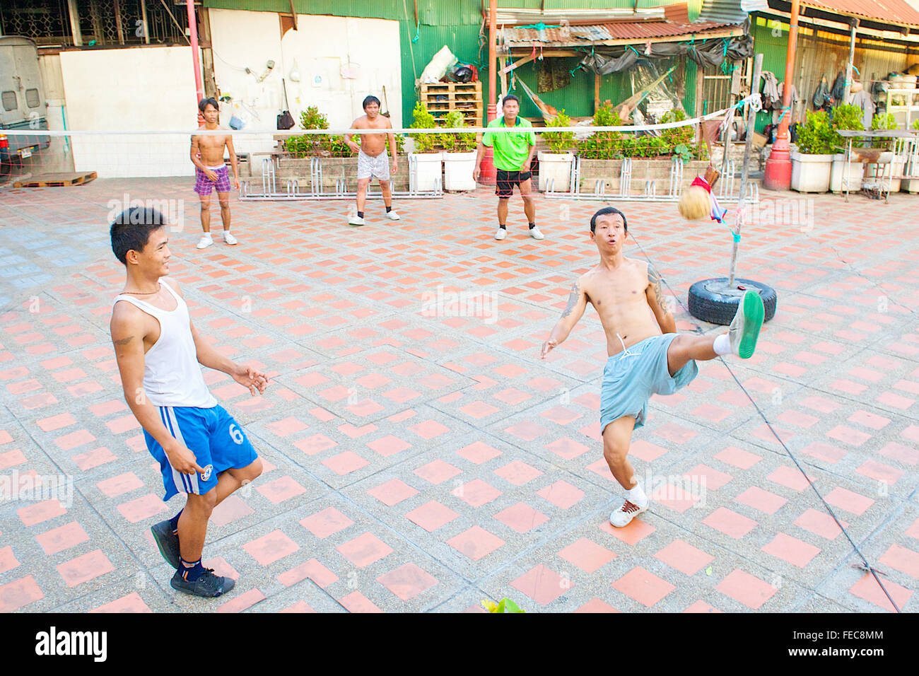 Thai men and boys playing Sepak Takraw or Kick Volleyball a volleyball game but with their feet in Bangkok, Thailand. Stock Photo