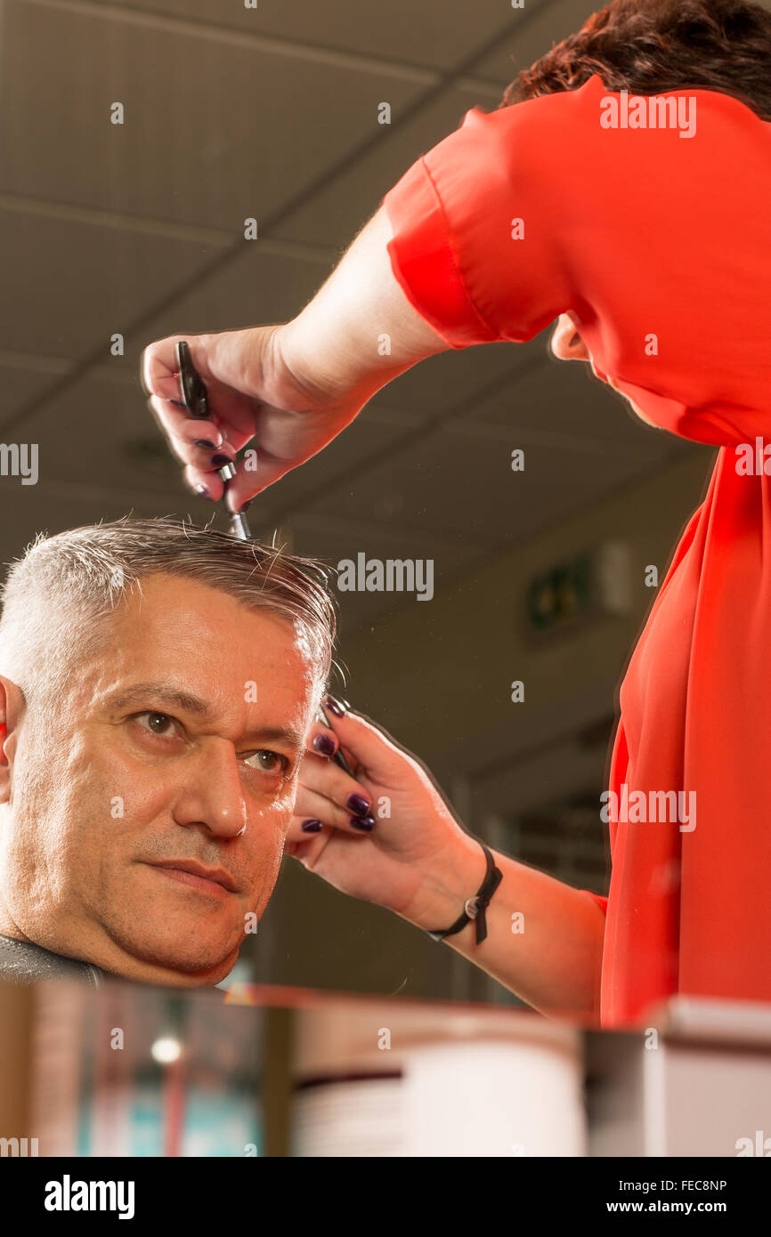 woman cuts hair with scissors, razor in professional hairdressing salon