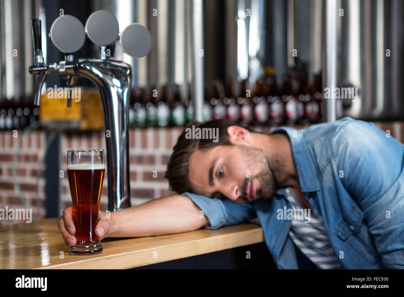 Tired man leaning on counter Stock Photo - Alamy