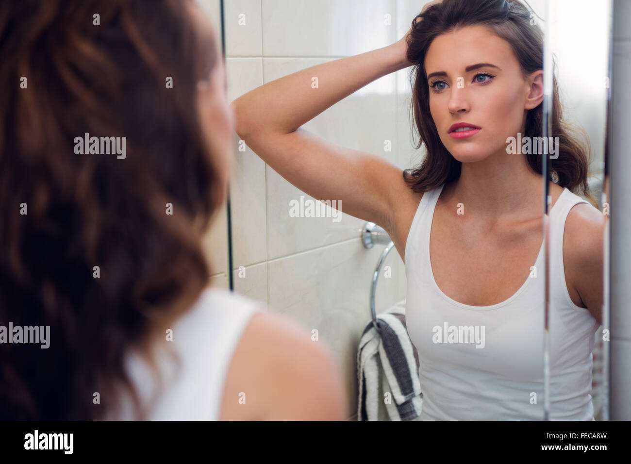 Beautiful Brunette Looking At Herself In The Bathroom Mirror Stock