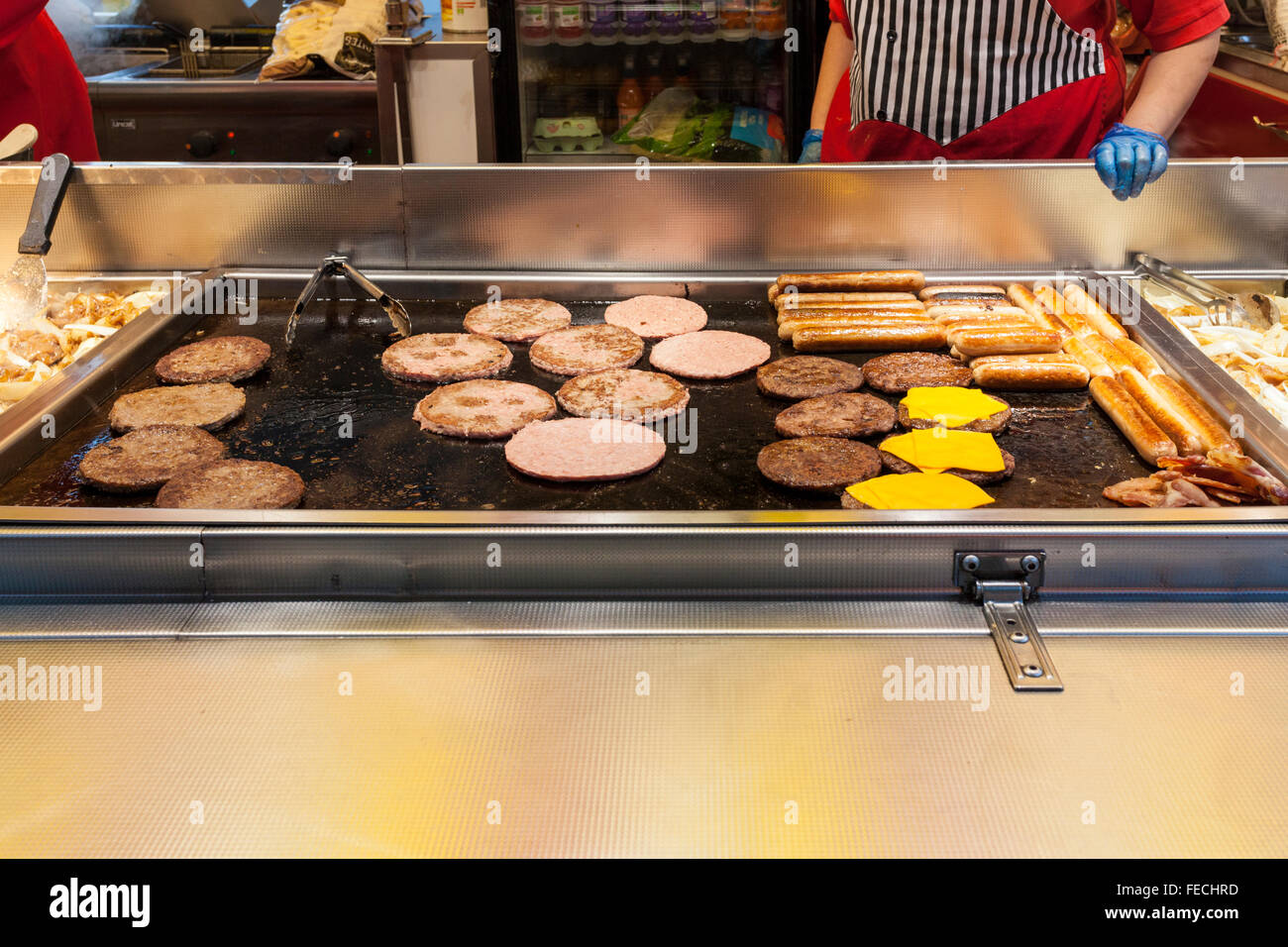 Fast food takeaway. Cooking sausages and burgers on a griddle to take away. Outdoor catering at Goose Fair, Nottingham, England, UK Stock Photo