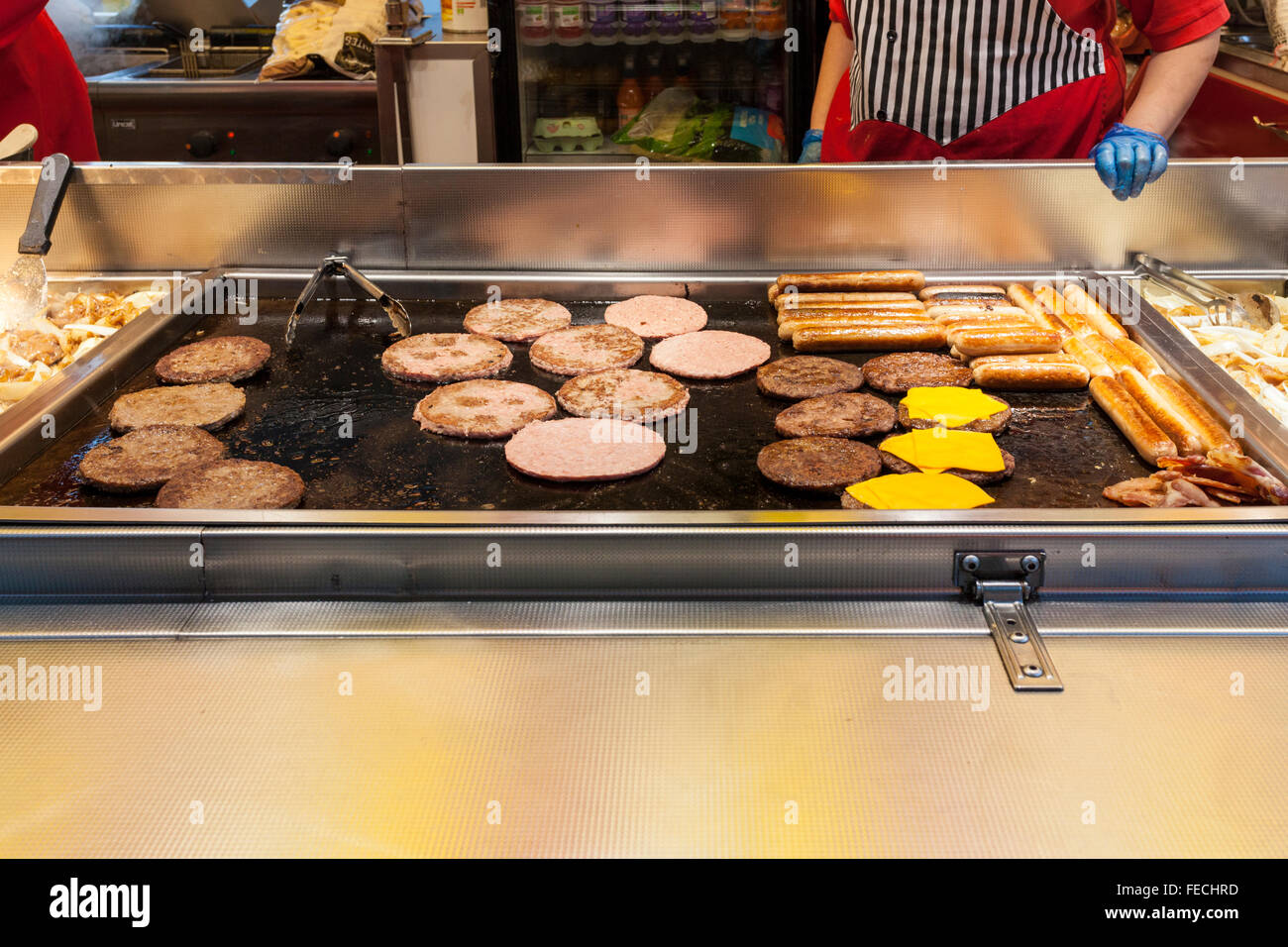 Fast food takeaway. Cooking sausages and burgers on a griddle to 