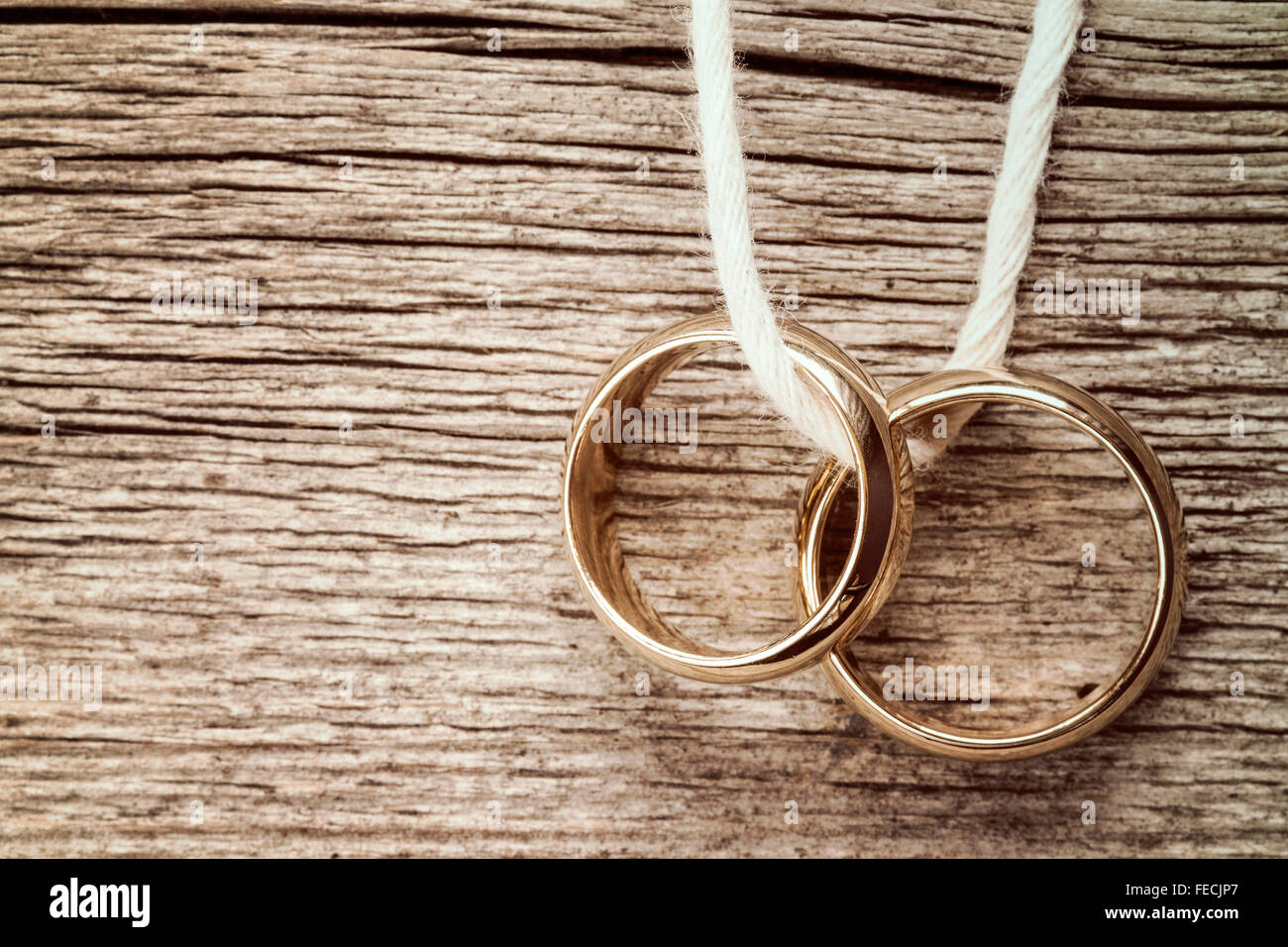 Wedding rings hanging on rope over wooden background. Vintage image ...