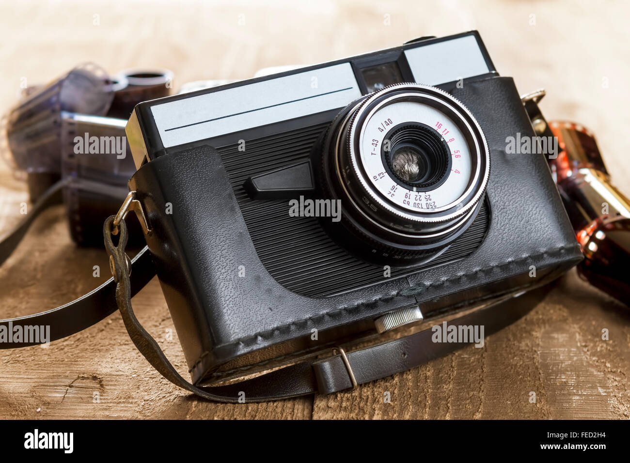 old camera and blank film strip on wooden table Stock Photo