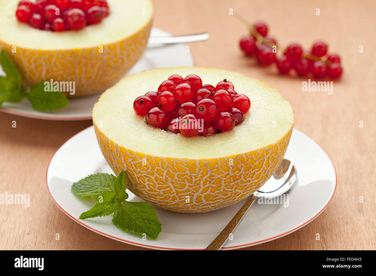 Melon filled with red currants for dessert Stock Photo