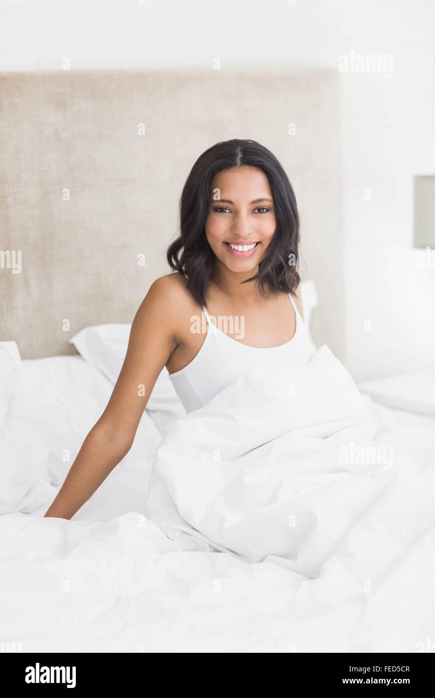 Smiling woman sitting on the bed Stock Photo - Alamy