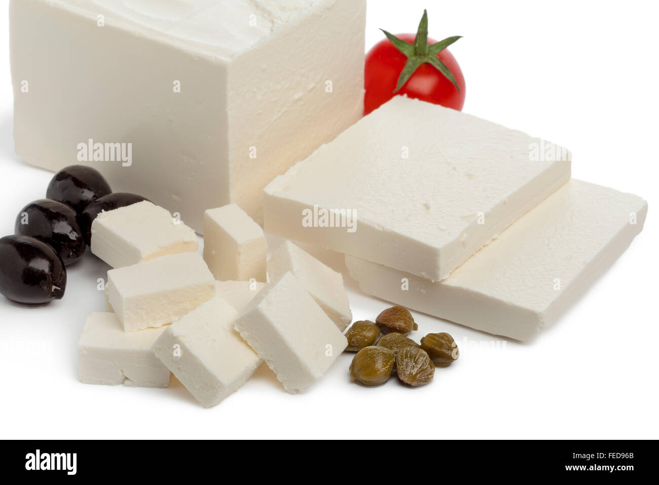 Fresh Feta cheese with slices and cubes, capers,tomato and black olives on white background Stock Photo