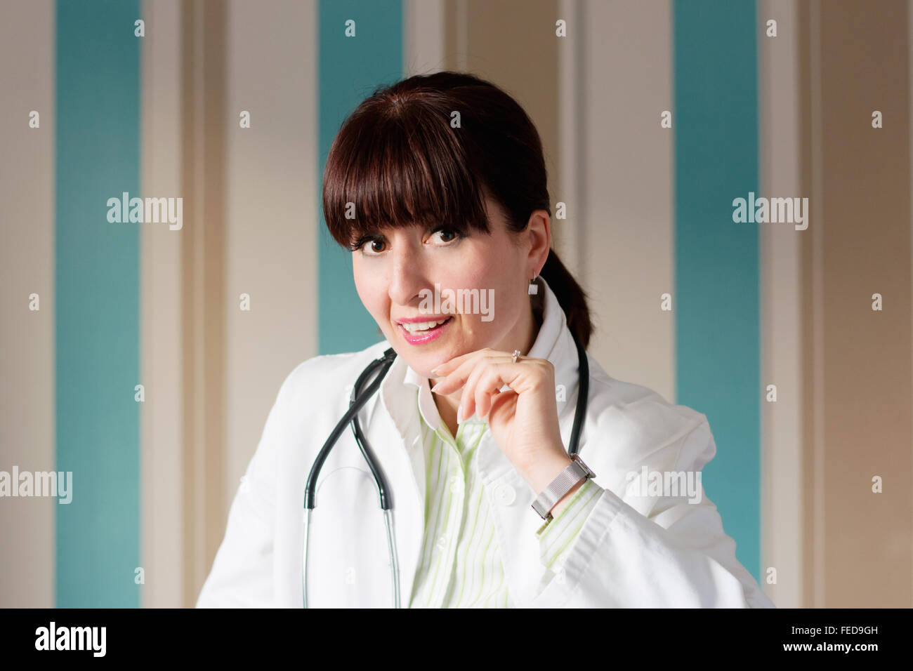 Female brunette doctor with bangs posing for the camera wearing scrubs and  stethoscope Stock Photo - Alamy