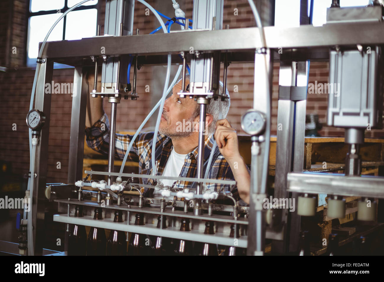 Happy brewer using machine equipment Stock Photo - Alamy