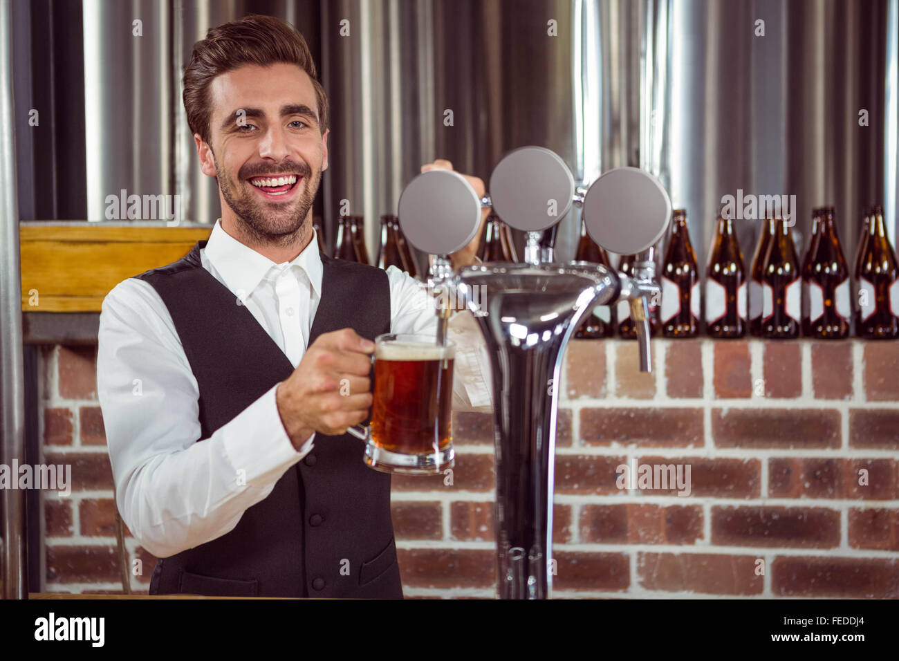 Handsome barman pouring a pint of beer Stock Photo