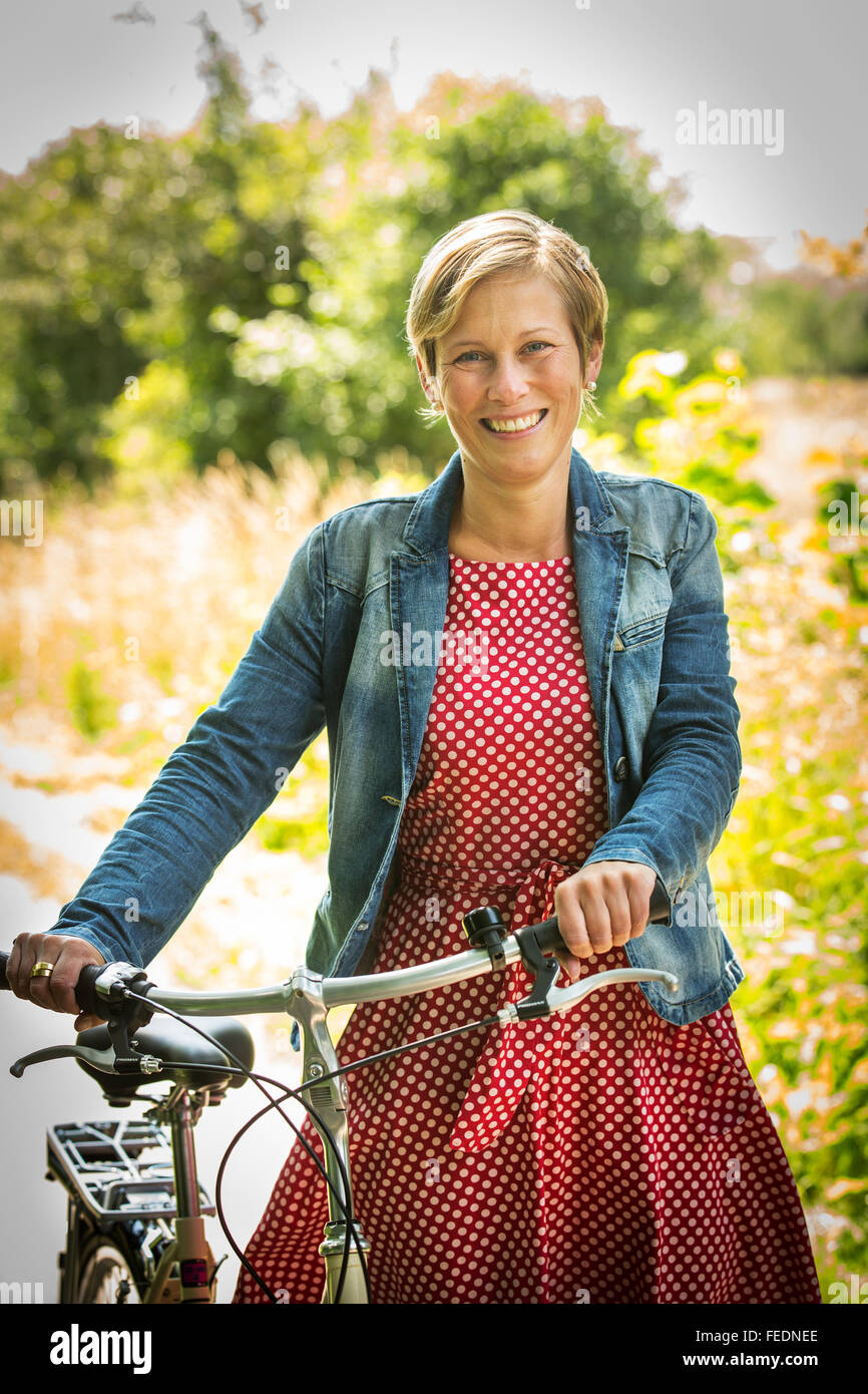 Laughing woman with her bicycle in nature Stock Photo