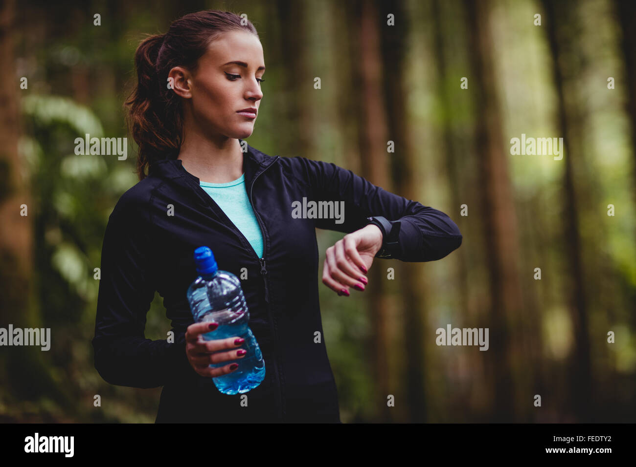 Fit brunette holding bottle and check her heart rate Stock Photo
