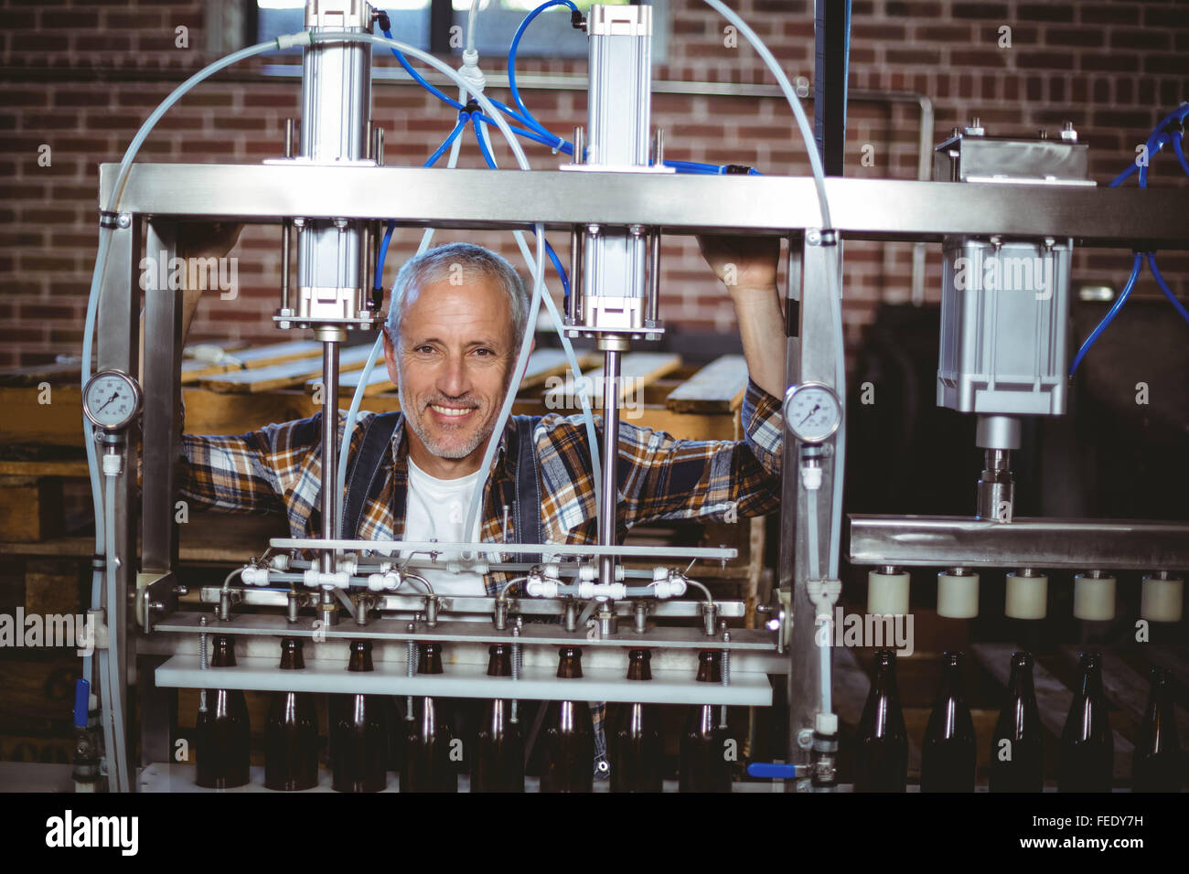 Happy brewer using machine equipment Stock Photo - Alamy
