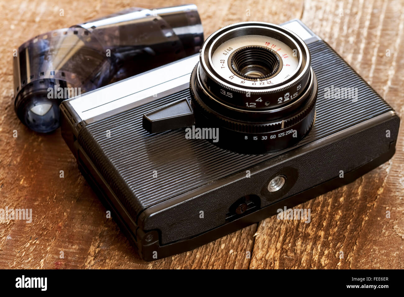 Old camera and blank film strip on wooden table Stock Photo