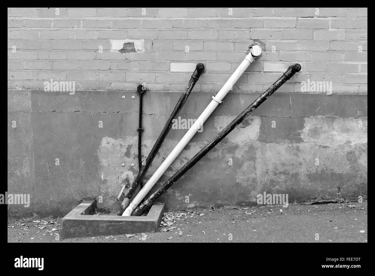 A photo of black and white angular water pipes on a beige brickwork wall in Europe Stock Photo
