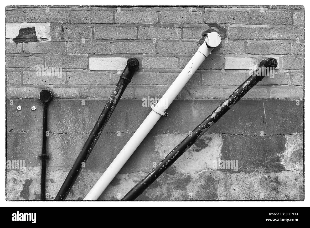 A photo of black and white angular water pipes on a beige brickwork