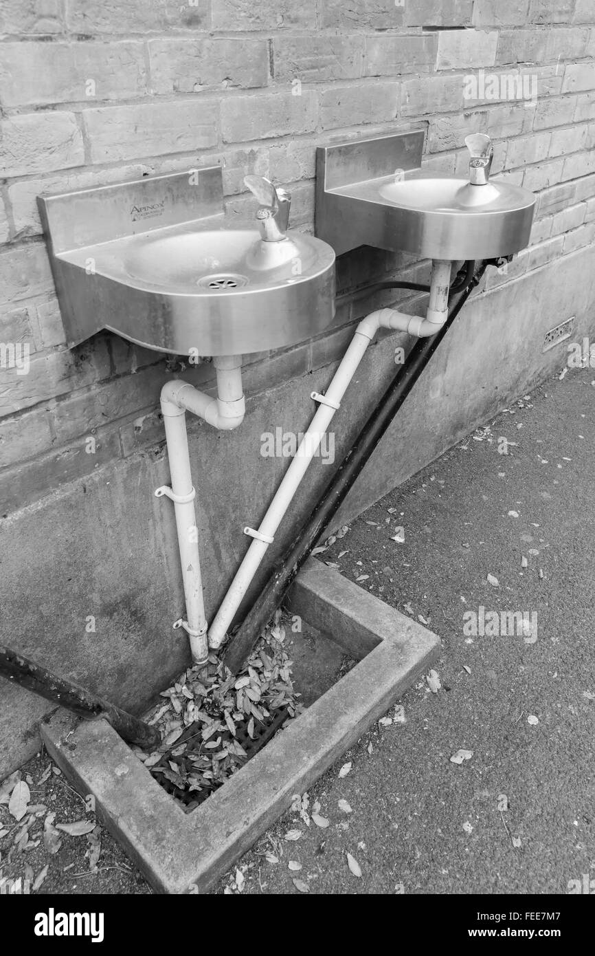 A photo of black and white angular water pipes connected to two stainless steel basins on a