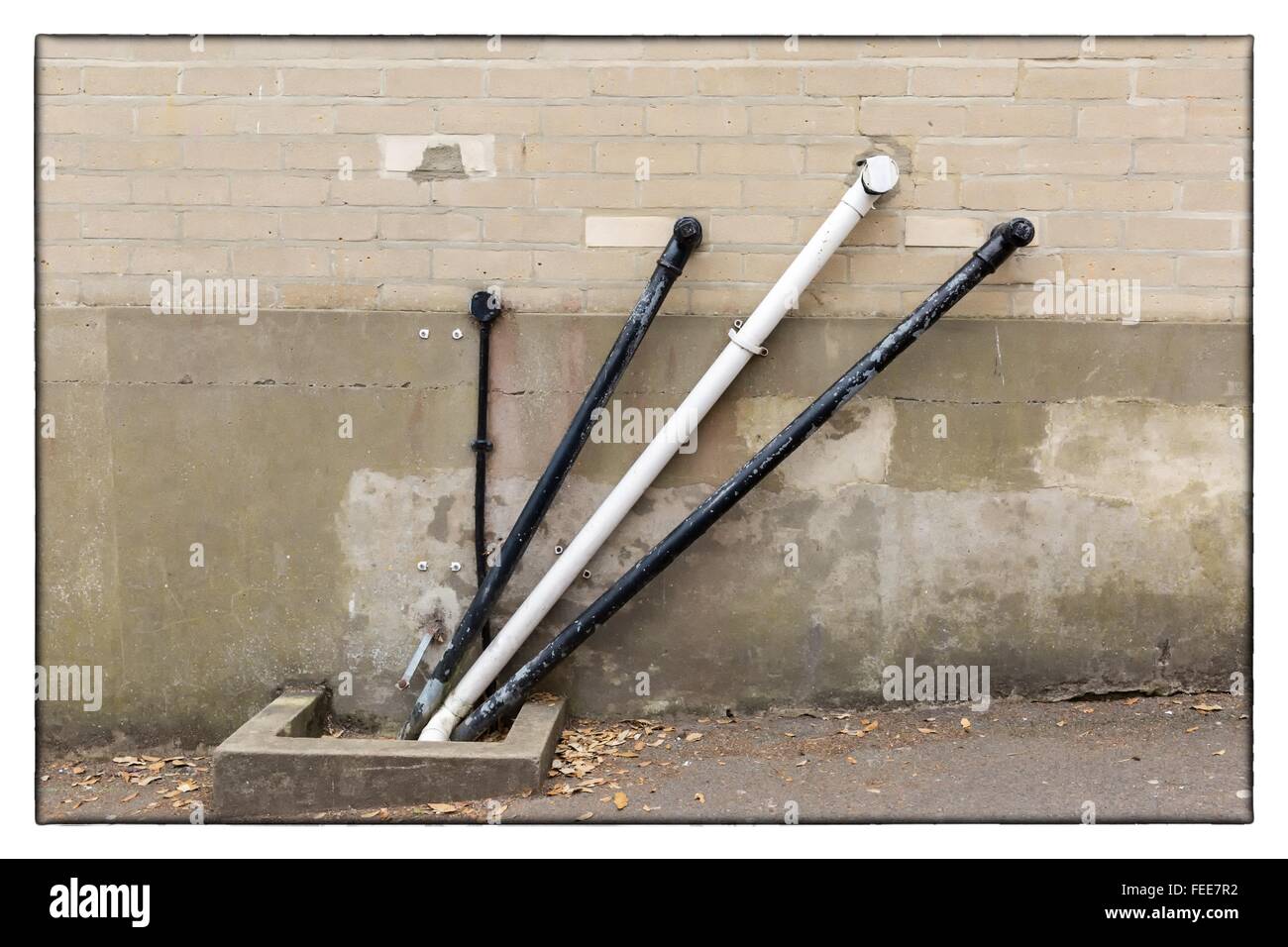 A photo of black and white angular water pipes on a beige brickwork wall Stock Photo