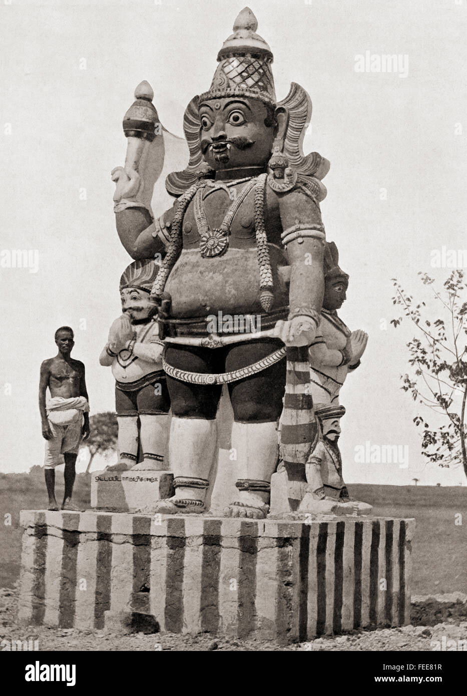 A village deity. A colossal statue of the gate-keeper god or Dvarapala,holding a gadha mace and with his attendants, in Tamilakam or the Ancient Tamil country, southern India. Stock Photo