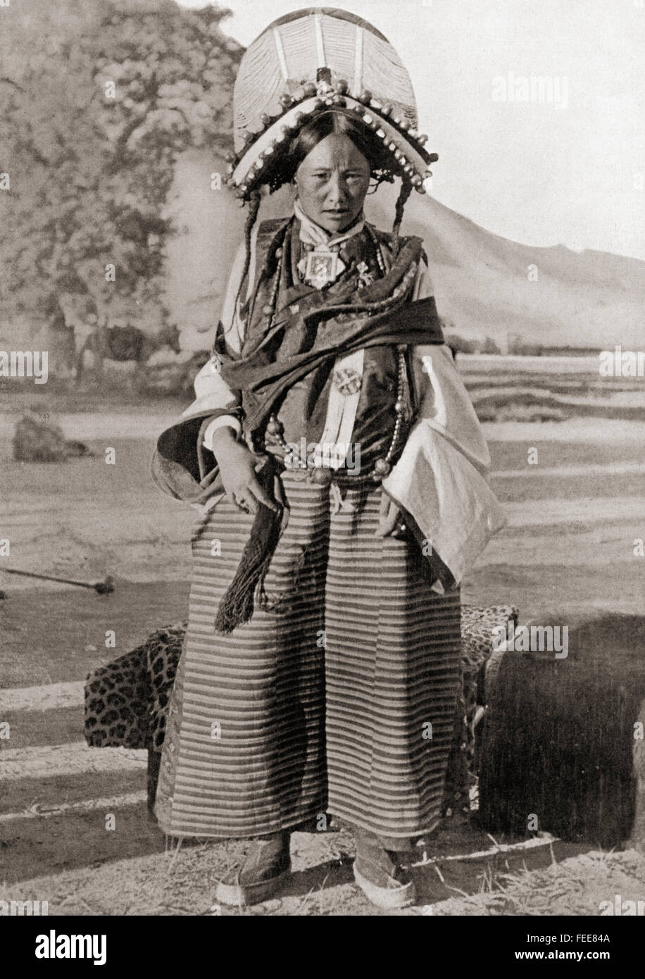 A woman from western Tibet wearing traditional dress.  The headdress is covered with pearls, coral, turquoise and other uncut precious stones and glass beads.  Each stone has a special protective property against evil spirits.  The necklace carries an amulet box of charms.  After a 19th century photograph. Stock Photo