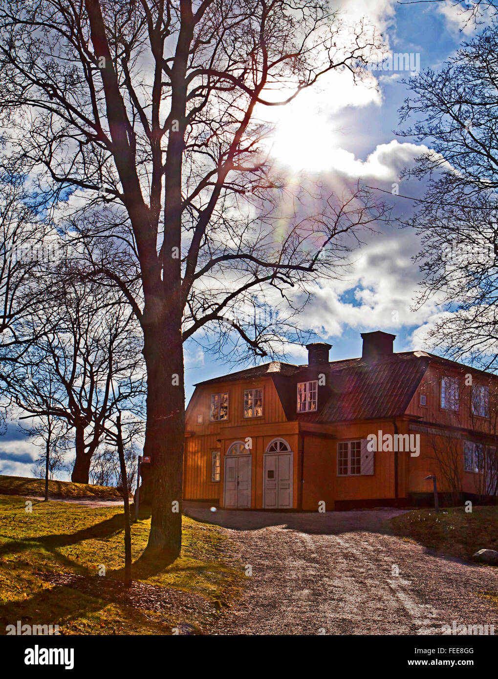 Sweden - Country house at Stockholm Waldemarsudde public park, back light  with sun rays and white clouds. Stock Photo